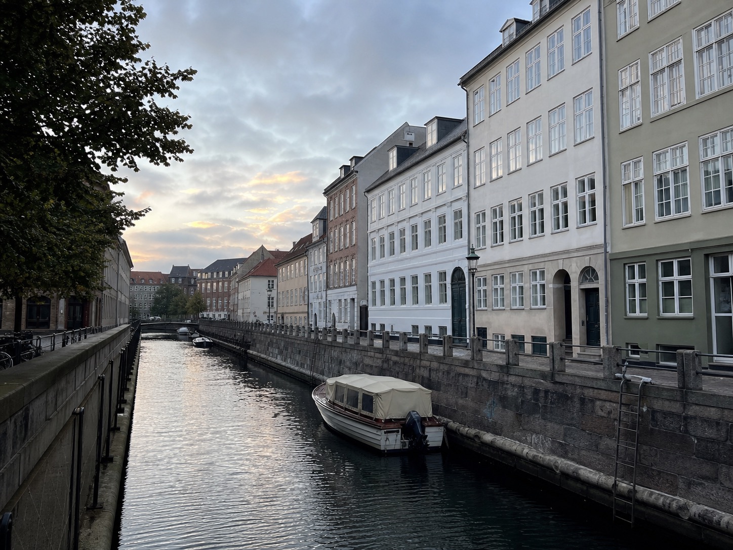 A quiet canal in Copenhagen with pale buildings reflected in the water
